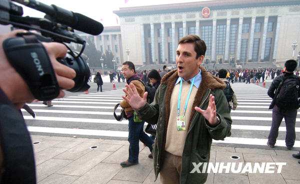 Avant la cérémonie d&apos;ouverture, un journaliste fait un reportage devant le Grand Palais du Peuple. 