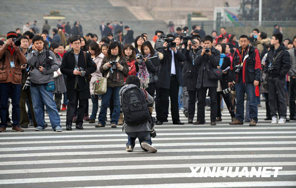 Avant la cérémonie d&apos;ouverture, un journaliste photographie ses confrères sur la place. 