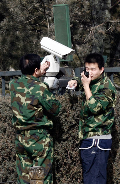 Deux membres du personnel examinent une caméra de surveillance sur la place Tian'anmen.