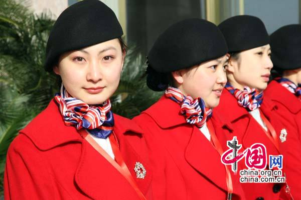 Sur la place Tian'anmen, des membres du personnel revêtues de costumes rouges, attirent l'attention des journalistes.