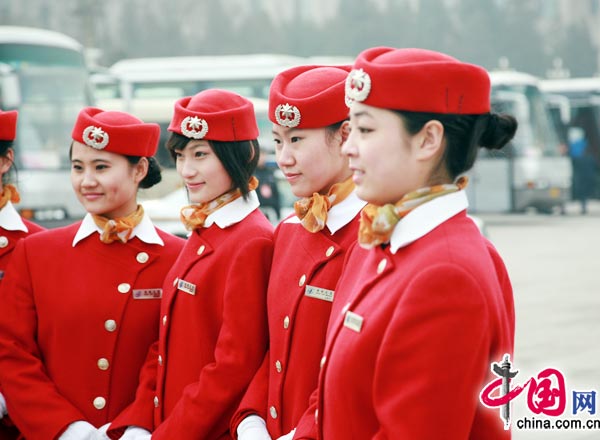 Sur la place Tian'anmen, des membres du personnel revêtues de costumes rouges, attirent l'attention des journalistes.
