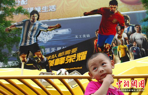 Beijing : dans la rue piétonne de Wangfujing, un jeune garçon pose devant une affiche géante de la Coupe du monde en Afrique du Sud.