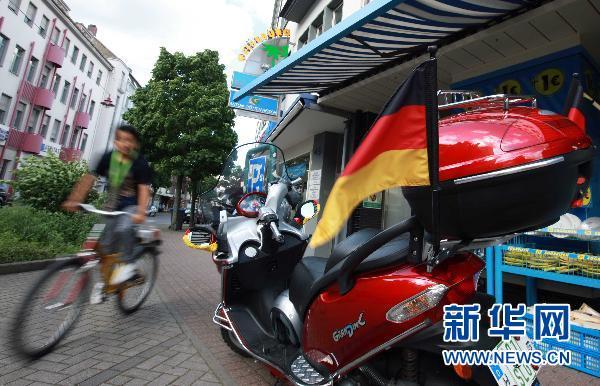 Un supporteur allemand décore sa moto avec son drapeau national.