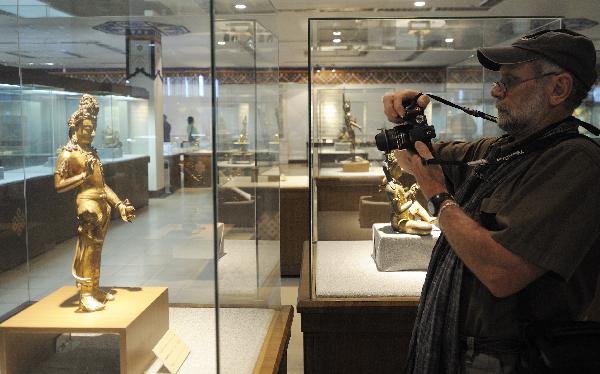 Un touriste étranger prend des photos d'une statue de bouddha dans le Musée du Tibet. Photo prise le 9 juillet.