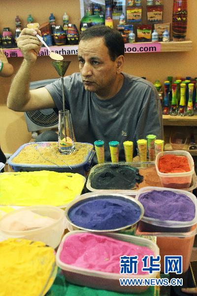 Le 12 août, un artiste du pavillon jordanien réalise une œuvre faite de sable pour les touristes.