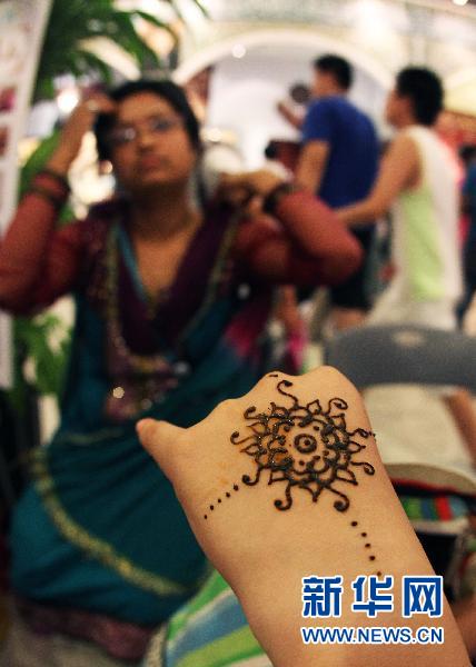 Le 12 août, une artiste du pavillon de l'Afghanistan fait une démonstration de henné traditionnel sur la main d'une touriste.