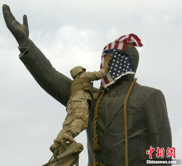 En avril 2003, un soldat américain recouvre la statue de Saddam Hussein du drapeau national des États-Unis. 