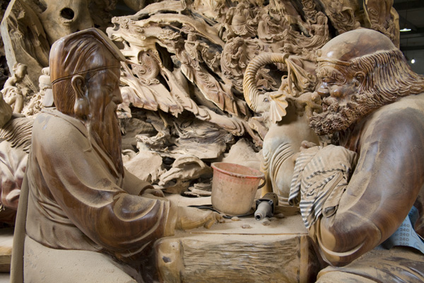 Deux statues en bois et des outils recouverts de sciure sur une table à jouer aux échecs