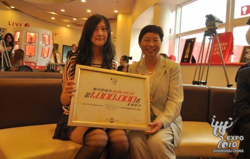 Le millionième visiteur Wang Qinlin (à gauche) pose pour une photo avec Li Xiaoyun, le vice-président de Coca-cola pour la Chine.