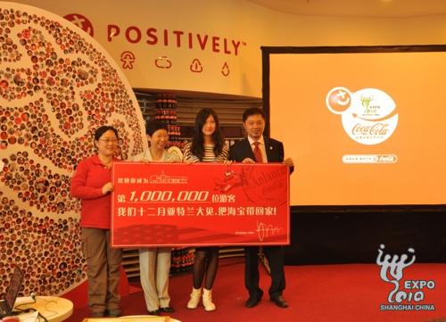 Wang et Li posent pour une photo derrière le certificat du millionième visiteur. Wang va s'envoler en décembre pour Atlanta, aux États-Unis, pour assister aux activités de clôture de l'heureux voyage mondial d'Haibao de Coca-cola.
