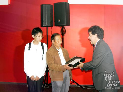 Le 7 millionième visiteur (au milieu), Fang Shixiong, reçoit les cadeaux des mains de José H. Villareal (à droite), le commissaire général du pavillon américain.