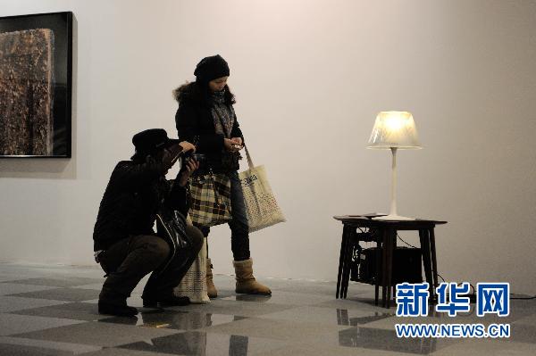 Un visiteur prend des photos d'une œuvre exposée.