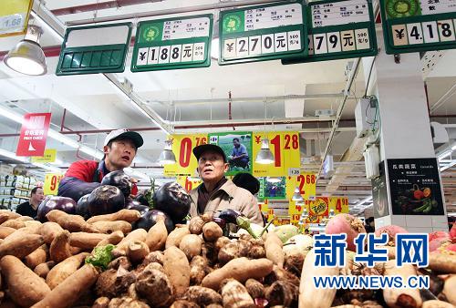Le 11 décembre, un employé aide un client à choisir des légumes dans un supermarché de Beijing.