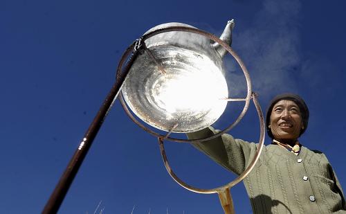 Une femme tibétaine fait chauffer de l'eau dans un four solaire. (Photo prise le 25 décembre 2010).