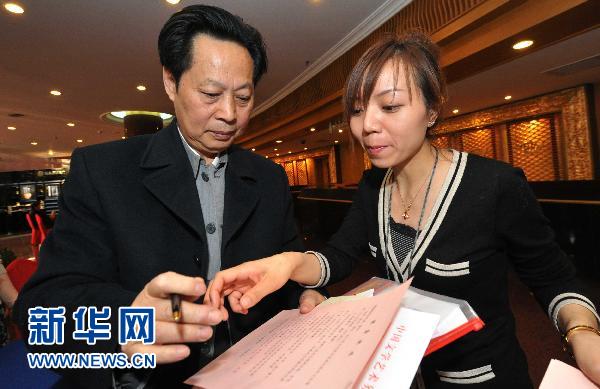 Le 1er mars, une employée de l'hôtel international de Beijing présente la carte de santé à Wang Xinguo, membre de la CCPPC (à gauche).