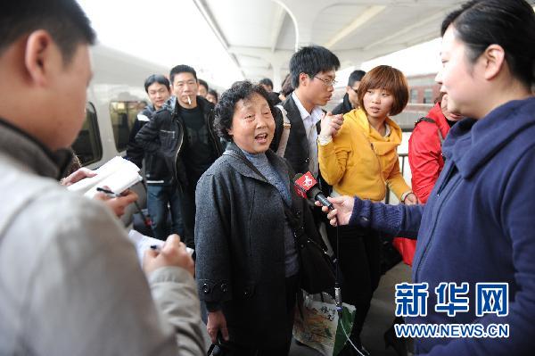 Une touriste de retour du Japon est interviewée par des journalistes à son arrivée à la gare de Nanchang.