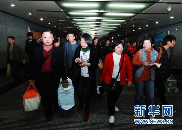 Des touristes de retour du Japon sont interviewés par des journalistes à leur arrivée à la gare de Nanchang.