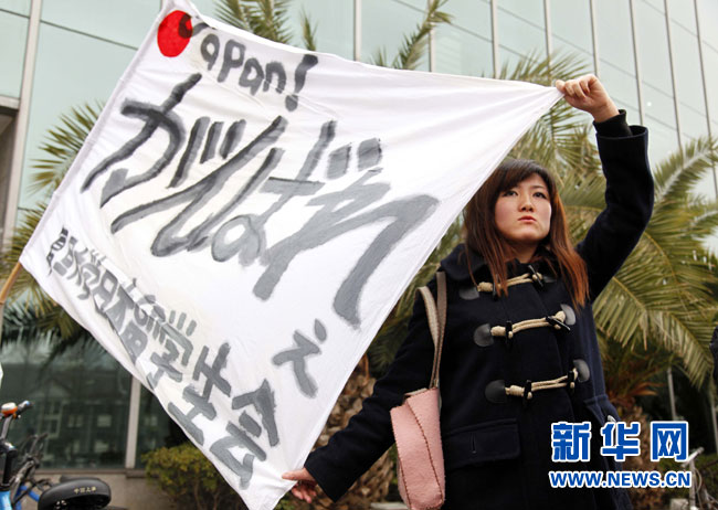 Au cours de la collecte, une étudiante japonaise porte haut le drapeau japonais sur lequel est écrit « Courage, le Japon ».