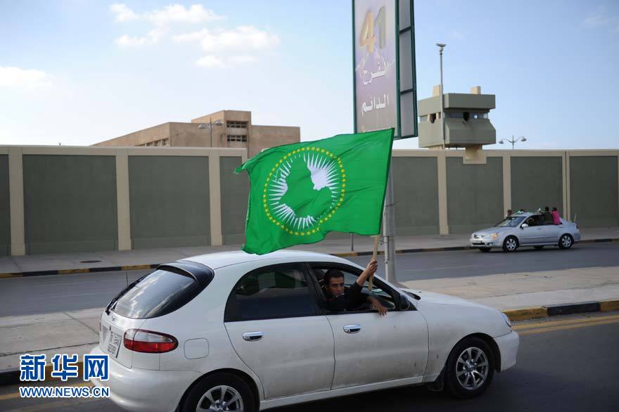 Le 19 mars, un homme passe en voiture devant le camp militaire Bab el-Aziziya en brandissant un drapeau vert. 