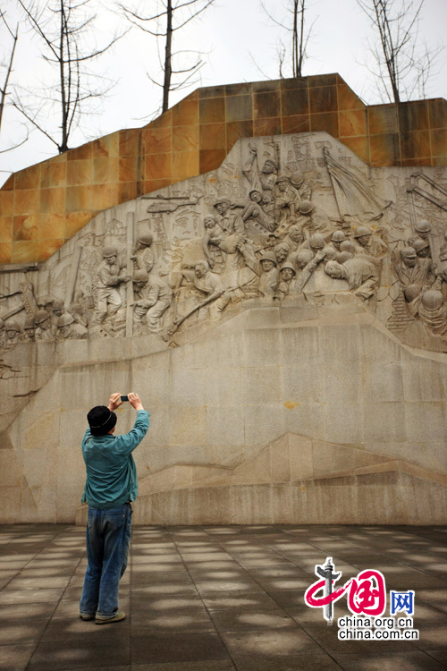 Un touriste photographie les sculptures murales. 