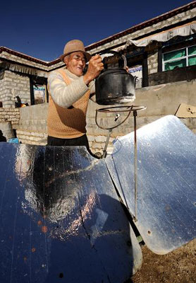 Un vieil homme tibétain fait chauffer de l'eau au four solaire, dans sa maison en banlieue de Lhassa. Photo prise le 16 décembre 2009.