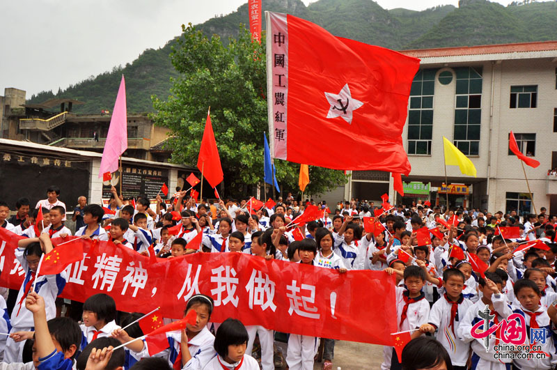  17 juin : des élèves du primaire et du secondaire assistent au relais du « flambeau rouge » en brandissant des drapeaux rouges.