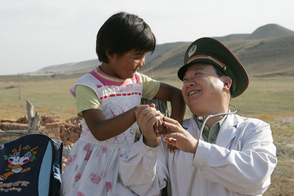 Sur cette photo d'archive, Zhuang Shihua, président de l'hôpital affilié au Corps de la Police armée du Xinjiang, tient la main d'un enfant qui est retourné à l'école grâce à son aide. 