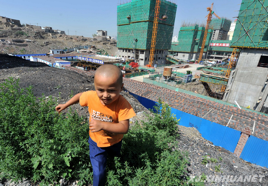 Le 5 juillet, un enfant passe devant le chantier de rénovation d'un bidonville à Heijiashan.