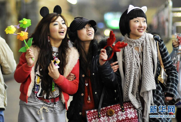 Trois jeunes femmes vêtues de manière personnalisée fêtent Noël dans une rue de Yichang de la province du Hubei, le soir du 24 décembre 2008.