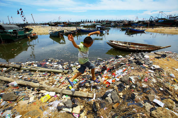 Un garçon joue sur une plage couverte d'ordures dans le village d'Auquan, province insulaire de Hainan, en juin. La plage est couverte d'ordures qui échouent des villages voisins sur des centaines de mètres.
