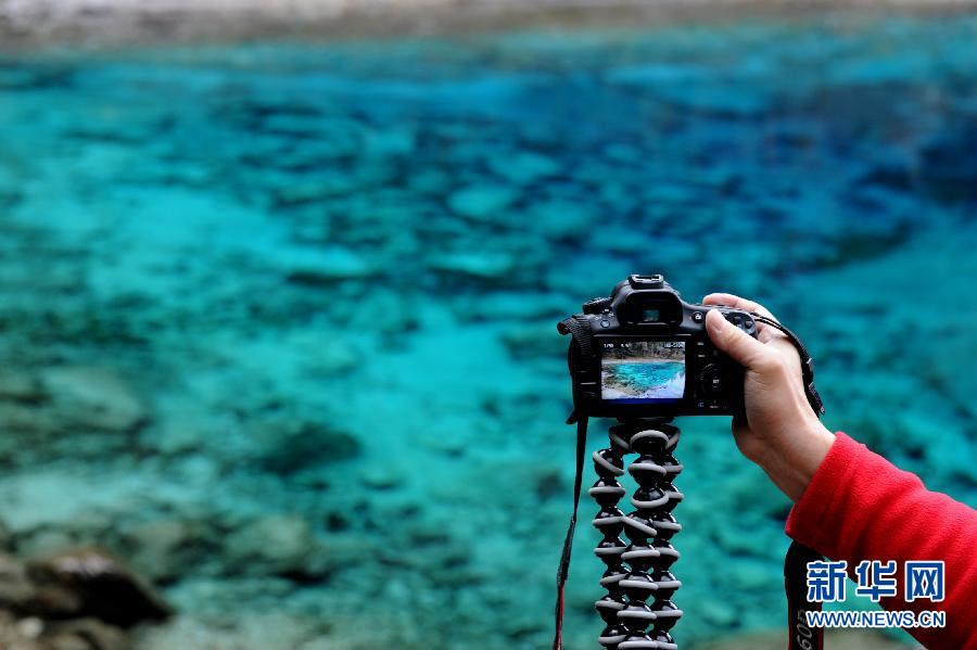 Le 20 octobre, des touristes prennent des photos près de Wucaishi (le lac multicolore) dans la zone touristique Jiuzhaigou de la province du Sichuan (sud-ouest de la Chine).