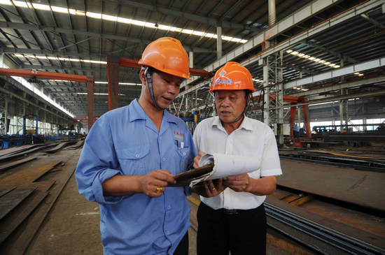 Le 23 août 2012 dans le village de Jiangxiang au Jiangsu, le délégué au 18e Congrès du Parti communiste chinois, Chang Desheng, discute avec un ouvrier à l'usine d'acier coloré appartenant au village de Jiangxiang, à Changshu dans la province du Jiangsu.