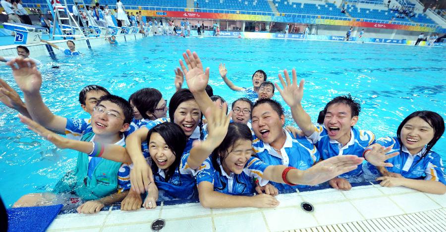 Le 15 septembre 2008, les bénévoles célèbrent la fin des épreuves de natation aux Jeux paralympiques de Beijing en sautant dans l&apos;eau. 