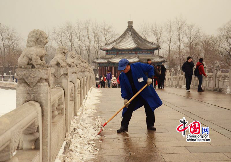 Le 20 janvier, un ouvrier nettoie la neige sur le pont aux Dix-Sept Arches enneigé au Palais d&apos;été à Beijing. (Crédit photo: Zhu Ying)