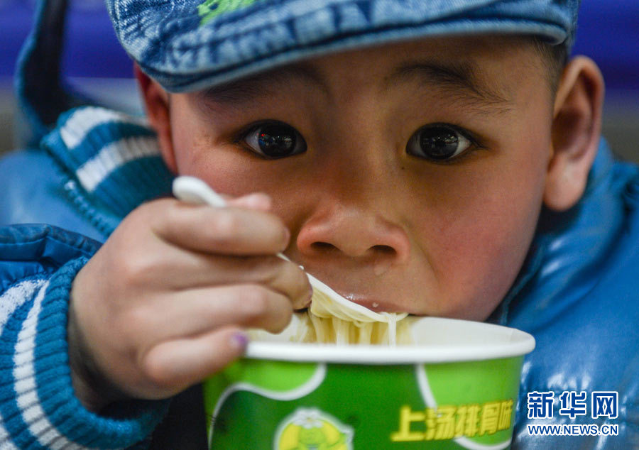 Les nouilles instantanées. Le 22 janvier, Zhao Yongchun, 5 ans, savoure des nouilles instantanée alors qu'il attend le train à la gare de Hangzhou.