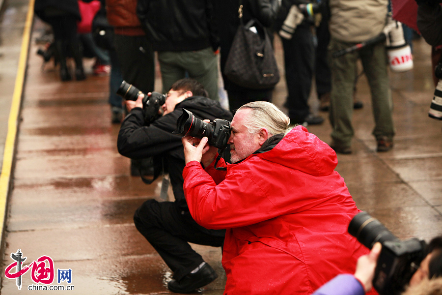 Des journalistes travaillent sous la pluie. 