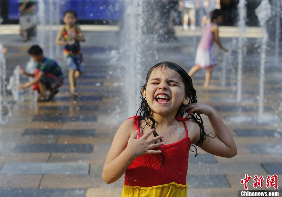 À Beijing, des enfants s'amusent dans une fontaine du quartier de Sanlitun.