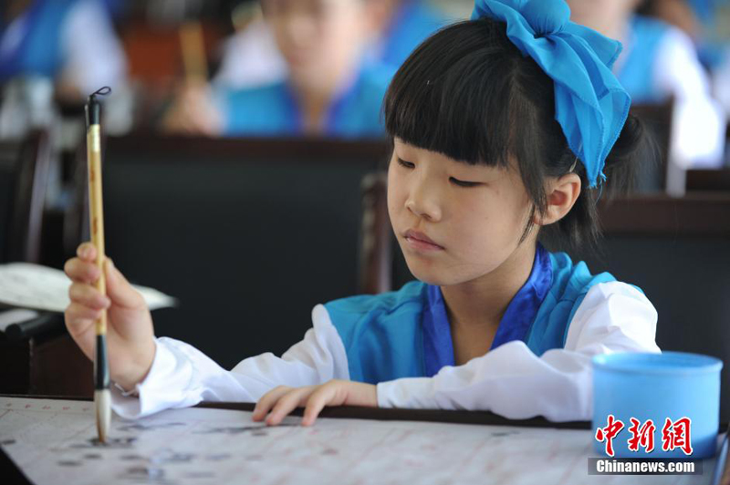 Un cours de calligraphie en tenue traditionnelle chinoise