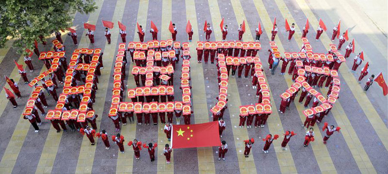 Des écoliers se prennent en photo avec le drapeau national à Linyi, dans la province du Shandong, le 30 septembre 2014. [Photo : Xinhua]