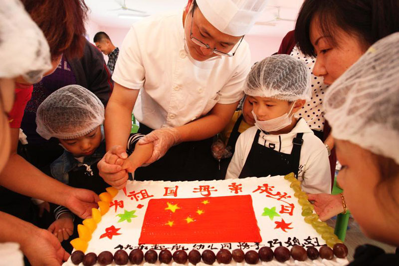 Un pâtissier confectionne un gâteau d&apos;anniversaire décoré du drapeau national pour célébrer la fête nationale à Yantai, dans la province du Shandong, le 30 septembre 2014. [Photo : Xinhua]