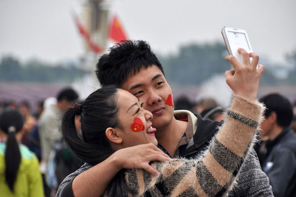 Deux touristes se prennent en photo sur la place Tian'anmen, le 1er octobre 2014, premier jour des vacances de la fête nationale. [Photo : Xinhua]