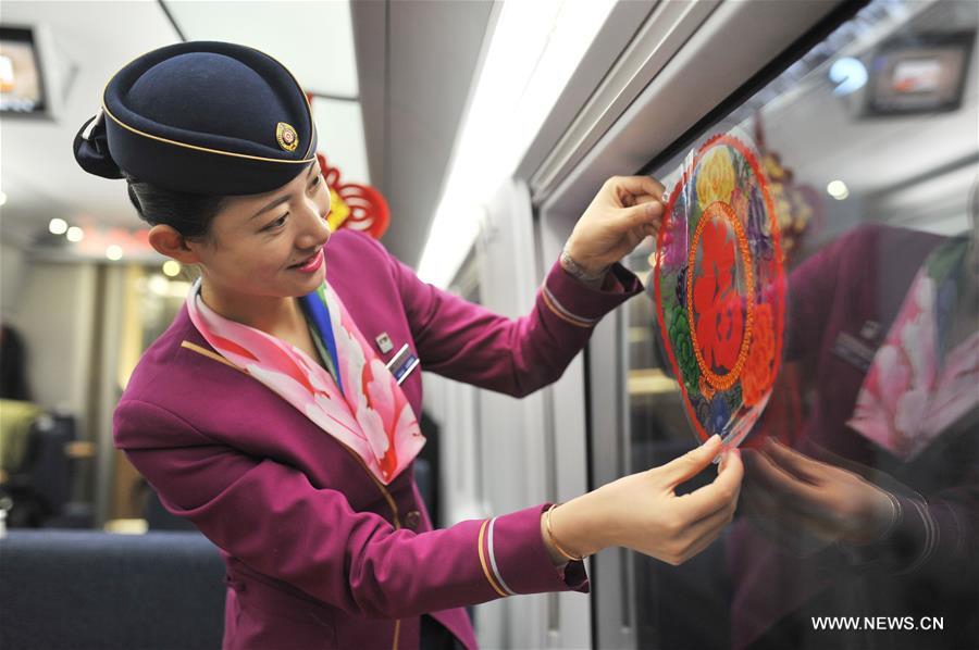 Une hôtesse de train colle des décorations de fenêtre sur un train partant de Qingdao, dans la province du Shandong (Est de la Chine) à destination de Beijing, pour célébrer la prochaine Fête du Printemps, le 30 janvier 2016.