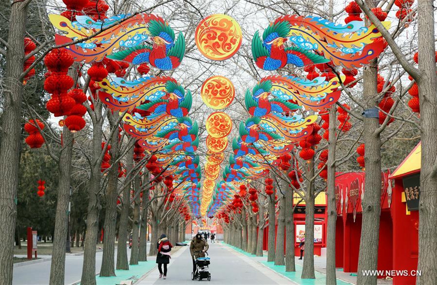 Des promeneurs passent sous des décorations nouvellement installées dans le parc Ditan de Beijing pour célébrer la prochaine Fête du Printemps, le 30 janvier 2016.