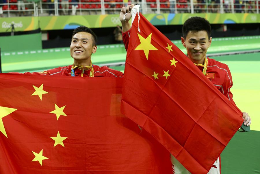 Le Chinois Dong Dong (à gauche), médaille d&apos;argent, et son compatriote Gao Lei, médaille de bronze, posent avec le drapeau national après la finale du trampoline masculin à Rio de Janeiro, au Brésil, le 13 août 2016. [Photo Wei Xiaohao / chinadaily.com.cn]