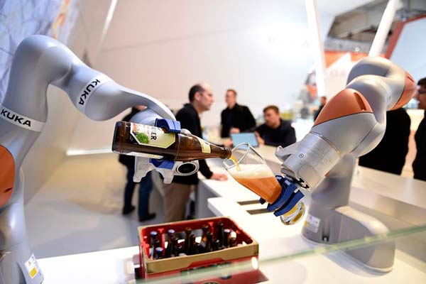 Des robots versent une bière dans un verre sur le stand de Kuka, lors du salon industriel Hannover Messe à Hanovre, en Allemagne, le 23 avril 2016. [Photo / agences]