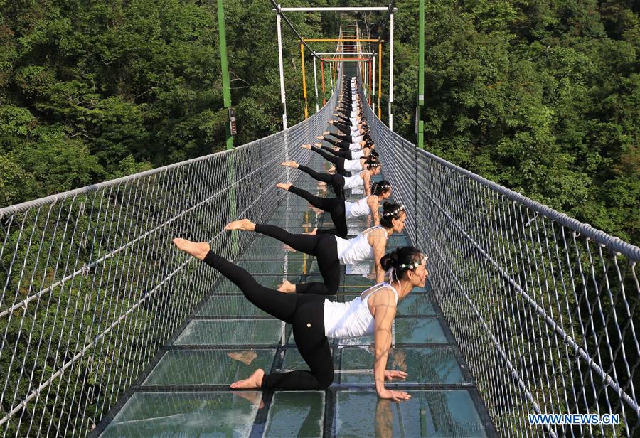Des yogis pratiquent le yoga sur un pont en verre dans le parc forestier de Shuanglonggou