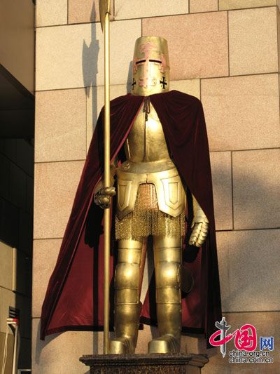 Ein goldener Ritter mit Umhang bewacht den Eingang.