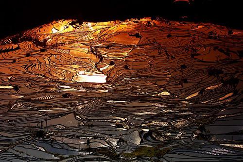 Man sagt, Yuanyang sei der beste Ort in Yunnan, um einen Sonnenuntergang zu fotografieren. Das Abendrot ist hier nicht nur im Himmel, sondern überall zu spüren. Der Wind singt dazu sein Lied und zieht über die bunten Terrassenfelder.