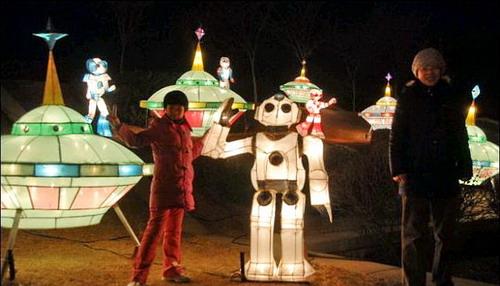Ein Kind lässt sich mit einem Laternenroboter beim Feuerwerk- und Lichtfest in Dalian fotografieren.