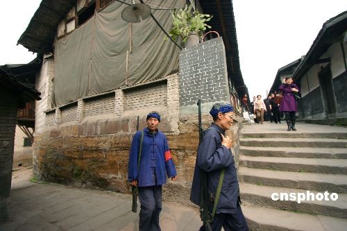 2 Zwei Patrouillen in Uniformen im Stil der 1930er Jahre marschieren durch die alten Stra?en von Songji in der südwestchinesischen Stadt Chongqing. Die mit Holzgewehren bewaffneten Patrouillen sind Teil des dortigen Kontrollprogrammes für die Nachbarschaft. Die Gemeinde wirbt mit ihnen au?erdem für touristische Zwecke.